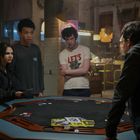 Ein Raum mit vier Personen um einen Pokertisch. Eine Person trägt ein T-Shirt mit "LET'S". Spielkarten und Chips sind auf dem Tisch.