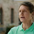 Ich kann leider nicht sagen, wer auf dem Bild ist. Eine Person in einem grünen Hemd gestikuliert. Hintergrund unscharf.