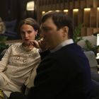 Eine Frau in einem weißen Outfit mit dem Text "DG" sitzt in einer stilvollen, gedämpft beleuchteten Lounge.