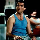 Es gibt keinen sichtbaren Text. Ein Mann in einem blauen Tanktop sitzt nachdenklich in einem Fitnessstudio.