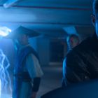 Ein Mann in Lederjacke steht in einer blauen, unterirdischen Garage. Hinter ihm sind Blitze und zwei Personen.