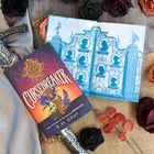 "Cursesbreaker" von R.M. Gray ist in dekorativer Schrift auf einem Buchcover mit lila und orange Verlauf, Blumenmotiv.