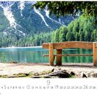 "Pragser Wildsee" sichtbar, darunter Monatskalender mit hervorgehobener Zahl 9. Holzbank vor smaragdgrünem See und Bergkulisse.