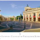 "Piazza del Campidoglio". Sonniger Platz mit Statuen und historischen Gebäuden, dekoriert mit rot-weißen Bannern.