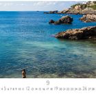 „Cala Blanca“, Monatskalender September mit Küstenlandschaft, Felsen und klarem Wasser. Eine Person im Meer.