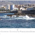 „Puerto de la Cruz“ steht unten links. Stadtansicht mit Häusern, Meer im Vordergrund und Bergen im Hintergrund.