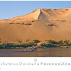 Zahlen von 1 bis 30 am unteren Rand. Große Sanddünen im Sonnenlicht, unten Fluss und grüne Vegetation.