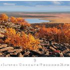 Herbstlandschaft, Monatszahl 9.  
Goldene Blätter vor felsiger Landschaft, im Hintergrund ein See und Wälder.