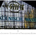 „4711“, „KÖLNISCH WASSER“ und „KÖLN HBF“ sind sichtbar. Glasfassade mit Metallstruktur im Hintergrund.