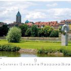 Schweinfurt, Mainpromenade. Eine Grünfläche mit einem Fluss, im Hintergrund eine Stadt mit roten Dächern und Türmen.