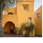 Text: "53, Casa Efraín González Luna." Gelbes Gebäude mit Torbogen und Treppe, umgeben von Pflanzen und Bäumen.