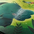 Text: "Jungle Kind"   
Eine fröhliche Illustration eines Elefanten in Grün mit rosa Wangen, umgeben von Pflanzen, Vogel und Biene.