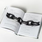 Offenes Buch mit Texten wie "SEI BRAV" und "REISS DICH ZUSAMMEN". Eine Illustration zeigt eine schwere Eisenkette quer über die Seiten.