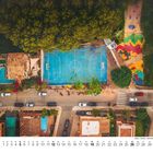 Kalenderdaten im September, blauer Sportplatz, bunte Spielfläche, grüne Bäume, Autos an der Straße.