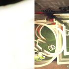 Links: Zahl "38" unten, verwischte Lichter einer nächtlichen Straße. Rechts: Graffiti auf der Wand mit hellen Buchstaben.