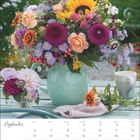 September, Tischkalender, bunter Blumenstrauß in grüner Vase, Tasse und Stoffserviette auf einem Tisch.