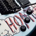 Text: "VOLUME," "TONE," "EMG." Zeichnung: Zwei Hippos und eine rote Sichel und Hammer-Skizze auf einer Gitarrenoberfläche.