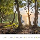 September 2023; Kalender mit Strandansicht durch Bäume im Morgenlicht. Das Meer und eine Klippe sind im Hintergrund sichtbar.