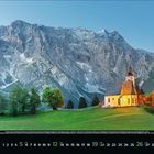 "9 2023. Eine beleuchtete Kirche vor einer Bergkulisse mit grünem Hang und Bäumen darunter."