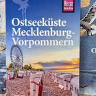 „Ostseeküste Mecklenburg-Vorpommern“, Reise Know-How Logo, Strandkörbe, Riesenrad, Sonnenuntergang am Strand.