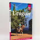 „Uruguay“ und „Reiseführer für individuelles Entdecken“. Ein Mann reitet ein Pferd vor einem weißen Gebäude.