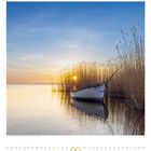 Ein Kalenderblatt für den September zeigt ein Boot im Schilf bei Sonnenuntergang auf einem stillen See.