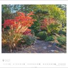 9 2027. Prächtiger Garten mit roten und grünen Pflanzen, Kiesweg in der Mitte, Sonnenlicht von oben.