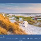 September 2027. Strand mit Strandkörben, Dünengras im Sonnenuntergang, ruhige Wellen im Hintergrund.