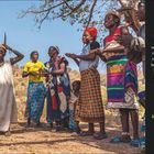 Koutammakou, Togo. Gruppe von Menschen in bunter Kleidung, tanzend und klatschend in einer ländlichen Landschaft.