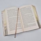 Das Buch liegt aufgeschlagen mit einer dahingelegten hellbraunen Lesehilfe. Es zeigt viel Text auf zwei Seiten.