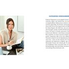 KATHARINA HINGSAMMER. Eine Frau sitzt an einem Tisch, schreibt in ein Notizbuch, vor ihr ein Laptop und eine Tasse.