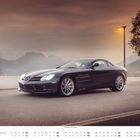 "SEPTEMBER", "Mercedes SLR McLaren". Ein elegantes Auto steht vor malerischer Bergkulisse und Laternenlicht bei Sonnenuntergang.