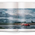 30, PORSCHE TRAVEL GUIDE, 31, ROUTE D'AZUR. Ein rotes Auto fährt vor einer Bergkulisse mit Wolken und Bäumen.