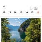 Juli, KW 28, Kalender: 12-18; Sonntag rot. Foto: Königssee, Bayern. Gerahmt von Bäumen, klare Aussicht auf See und Berge.