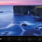 Irland 09, Kalenderdarstellung. Küste mit steilen Klippen und Meeresbögen bei Sonnenuntergang in sanften Blau- und Lilatönen.