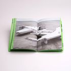 Das Bild zeigt ein aufgeschlagenes Buch mit grünen Seitenrändern, das eine abstrakte Skulptur darstellt.