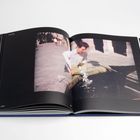 Text oben links: "Lucky Day". Unten links: "2006". Ein Mann mit weißem Hemd schöpft Wasser in einer sonnigen Straße.