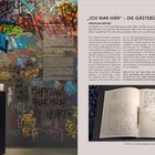 „ICH WAR HIER“ – DIE GÄSTEBÜCHER. EXIT THROUGH THE CITY. Bunte Graffiti an Wänden und ein offenes Gästebuch mit Kritzeleien.