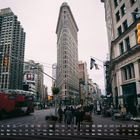 Flatiron Building, Kalender mit Zahlen und Wochentagen im Vordergrund, geschäftige Straßenszene mit Bussen und Fußgängern.