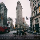 Kalender mit Datum und Wochentagen unten. Stadtansicht mit dem Flatiron Building, roten Bussen und vielen Fußgängern.