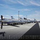 Kalendar mit hervorgehobenem 10. Tag. Mehrere Flugzeuge geparkt auf einem Flughafen bei klarem Himmel.