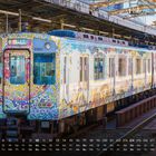 Kalender mit Zug im Hintergrund, verziert mit buntem Mosaikmuster. Oktoberdaten unten. Zug zeigt Richtung Osaka Namba.