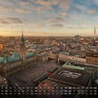 Kalenderansicht unten, darüber eine Stadtansicht bei Sonnenuntergang mit markanten Gebäuden und einem Turm.