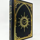 Auf dem Buchrücken steht "ALCHEMIST". Das Cover zeigt ein goldenes Sonnensymbol mit Mondsicheln, umrahmt von Ornamenten.