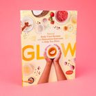 Buchcover: "GLOW" und "Natural Body-Care Recipes and Relaxation Exercises to Help You Shine" mit Händen, die eine Tasse halten.