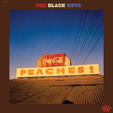 Text oben: "THE BLACK KEYS". 
Darunter ein altes Schild mit "Coca Cola" und "PEACHES!" auf einem Gebäude mit blauem Himmel.