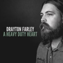 "DRAYTON FARLEY A HEAVY DUTY HEART" - Schwarz-Weiß-Porträt eines Mannes mit Bart und schulterlangen Haaren, seitlich betrachtet.
