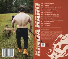 "KINDA HARD" und Titelliste. Ein Mann führt ein Schwein an der Leine über eine Wiese. Rückansicht.