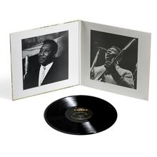 Das Bild zeigt eine geöffnete Schallplattenhülle mit Schwarz-Weiß-Fotos einer Person und eine schwarze Vinyl-Schallplatte.