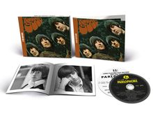 "Rubber Soul" und "2 CD Edition" auf braunen CD-Hüllen mit Porträts. Aufgeklapptes Buch zeigt Schwarz-Weiß-Fotos. Schallplatten.